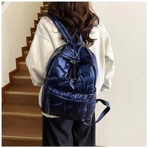Detail of navy blue quilted nylon backpack with padded texture and large front zipper pocket