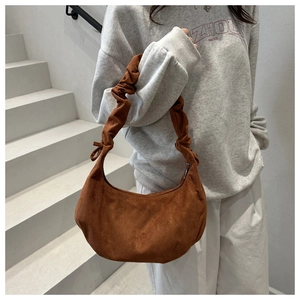 Detail of caramel suede hobo bag with pleated shoulder strap and small bow accent