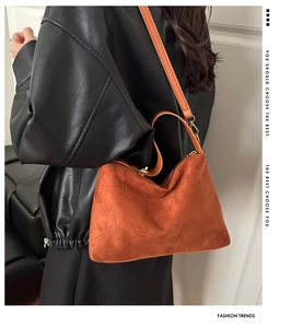 Detail of rust orange frosted suede handbag with golden hardware and shoulder strap
