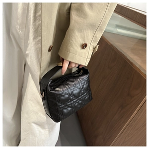 Detail of black quilted shoulder bag featuring heart pattern embroidery and metal zipper