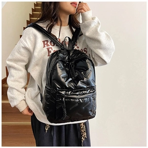 Detail of black quilted backpack with glossy waterproof texture and decorative zipper pull