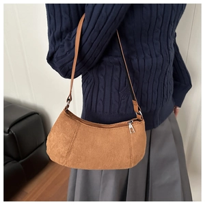 Sac hobo en daim marron vu de profil avec une forme de demi-lune élégante et chic