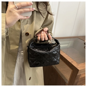 Mirror selfie showing the compact black heart-quilted handbag with a stylish trench coat