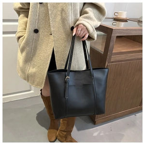 Détail du grand sac cabas noir en cuir PU porté avec un manteau beige élégant