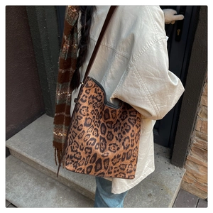 Outdoor shot of a large leopard print bucket tote bag with dark brown leather straps