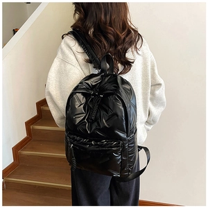 Rear view of model wearing a black quilted nylon backpack on everyday wooden stairs