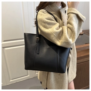 Detail of black PU leather tote bag showing adjustable metal buckle strap and front pocket