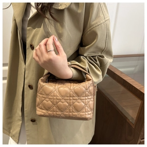 Close-up of beige quilted mini bag with elegant heart embroidery and metal D-rings