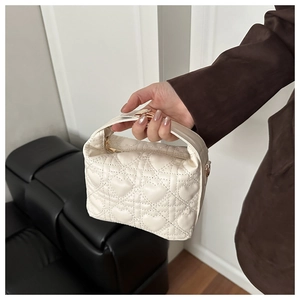 Detail of white heart quilted handbag featuring gold hardware and elegant top handle strap