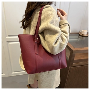 Detail of burgundy large tote bag with adjustable shoulder strap on a model