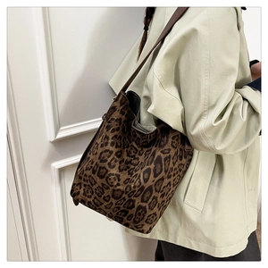 Detail of leopard print tote bag with brown leather straps shown on model's shoulder