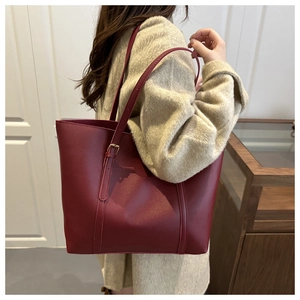 Détail du sac cabas en cuir bordeaux avec fine bandoulière et boucle en métal dorée