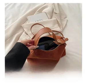 Spacious interior of brown suede bucket bag showing storage for phone and lipstick