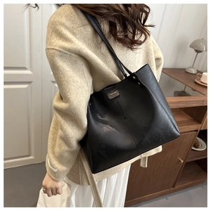 Close-up of black tote bag featuring soft lychee texture and metallic rivet detail