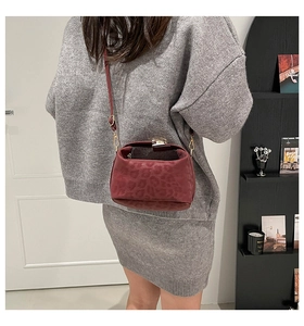 Detail of burgundy leopard print crossbody bag with metallic clasp and suede texture