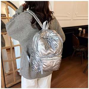 Detail of silver metallic quilted backpack with high-shine fabric and woven zipper puller
