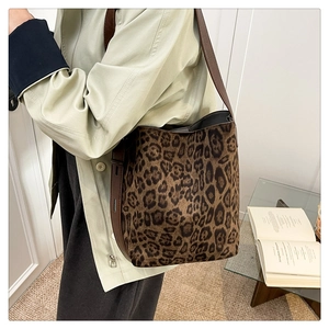 Détail du sac cabas léopard en daim avec bandoulière en cuir marron porté à l'épaule