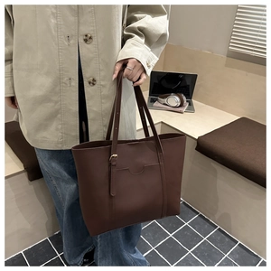 Détail d'un grand sac cabas en cuir mat marron foncé montrant sa capacité et son style chic