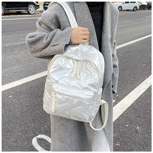 Detail of white quilted puffer backpack with glossy finish and woven zipper pulls