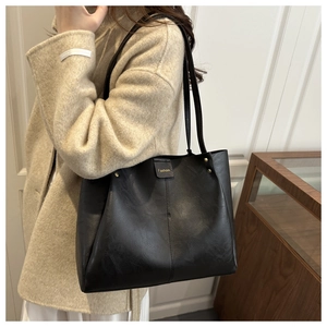 Close-up of black PU leather tote bag with Fashoin square patch and matte texture