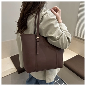 Side view of dark brown large leather tote bag with adjustable gold buckle on a model