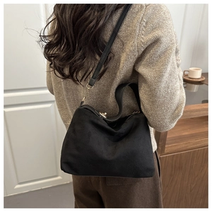 Detail view of the black matte textured hobo bag worn as a shoulder bag on a model