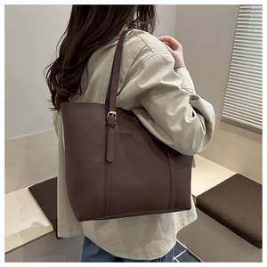 Macro shot of dark brown leather tote bag with vertical stitching and gold buckle detail