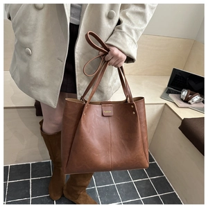 Detail of a large brown tote bag with magnetic flap closure and gold Fashion lettering
