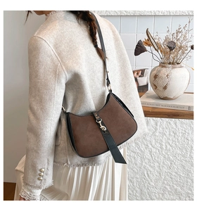 Detail of brown suede crescent hobo bag with black leather trim and gold metal buckle