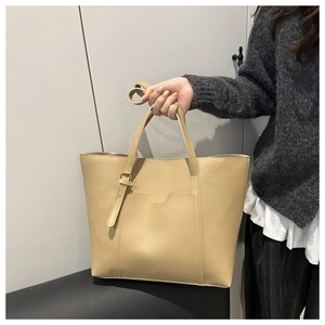 Detail of light beige matte leather tote bag with decorative metal buckle and strap