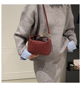 Model wearing a wine red leopard print handbag with a long strap and suede finish