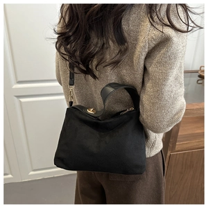 Detail of black suede shoulder bag with gold circular twist lock and wide strap