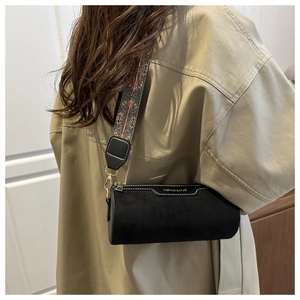 Detail of black cylindrical crossbody bag with colorful ethnic patterned wide strap