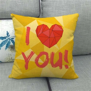 Close-up of yellow linen pillow with red geometric heart and I YOU text on gray sofa