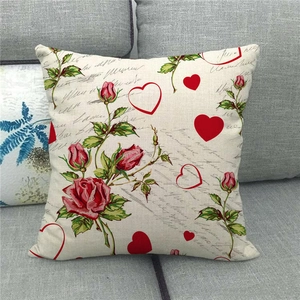 Close-up of linen pillowcase with red roses and heart patterns on a gray sofa