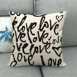 Detalle de funda de cojín de lino con estampado love sobre sofá gris de estilo moderno