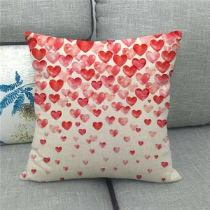 Funda de cojín cuadrada de lino con corazones en acuarela degradados rojos y rosas en sofá