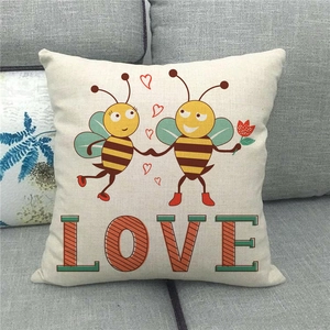 Detalle de funda de cojín de lino con abejas de dibujos y texto LOVE en sofá gris