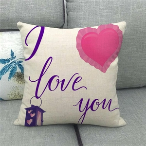 Close-up of linen pillow cover with I love you text and purple lantern on a gray sofa