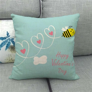 Close-up of linen Valentine's Day pillow cover with bees and hearts on grey sofa