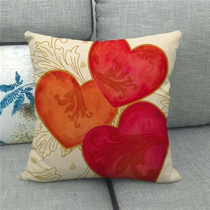 Linen pillowcase with vintage red heart patterns and gold vines on a gray sofa