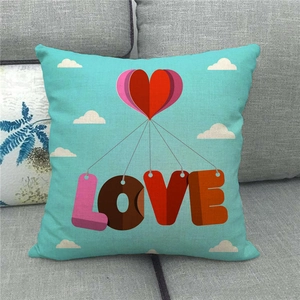 Close-up of cyan linen pillowcase with stacked heart patterns and LOVE text on grey sofa