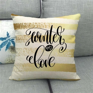 Close-up of a linen pillowcase featuring Winter AND Love text on a modern grey sofa