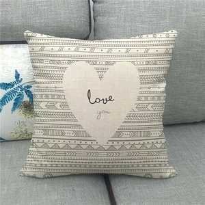 Linen pillowcase with love you text and geometric heart on a gray fabric sofa