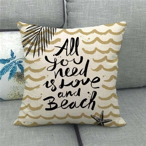 Close-up of linen pillow cover with All you need is love and Beach text and sea patterns