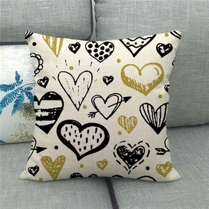 Linen blend throw pillow cover with golden and black heart patterns on grey sofa