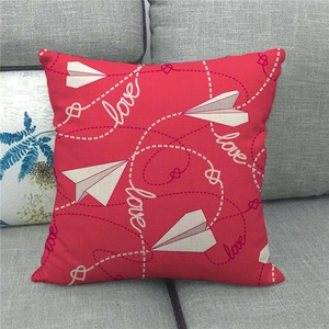 Detail of red linen pillowcase with paper plane and love text on grey sofa