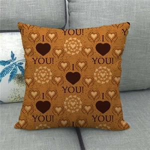 Close-up of linen pillowcase with heart patterns and I Love You text on a sofa