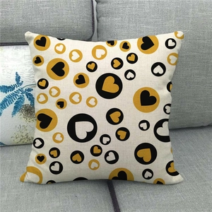 Close-up of linen cushion cover with black and gold heart pattern on a grey sofa