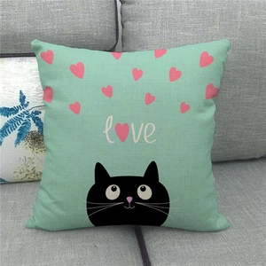 Close-up of linen pillow cover featuring a black cat and pink hearts on a grey sofa